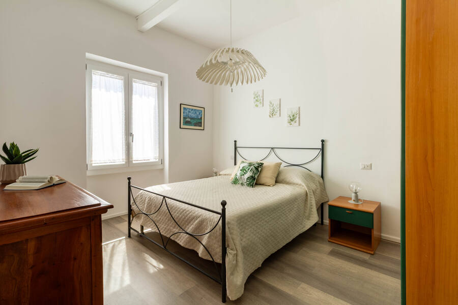 Camera da letto con testiera in ferro battuto e lampada a sospensione in legno